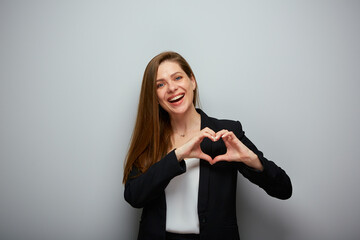 Smiling business woman in black suit holding heart figure with fingers, isolated portrait.