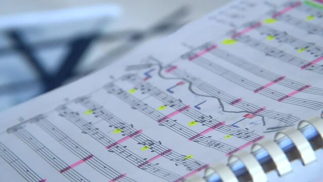Book with score for orchestra. Conductor's notes. Notebook. Classical music for orchestra. Musical notation on paper. Music stand. School of Music