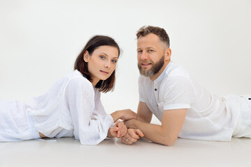 Portrait of sporty family lying after training on white background. Middle-aged man holding hands of young woman. Sport.
