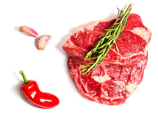 Fresh premium rib eye steak on white isolated background with green herb and garlic clove and red pepper. Premium beef cut. Top quality meat.