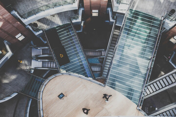 Drone point of view shot of a office, shopping mall with stairs and elevators, people walking by