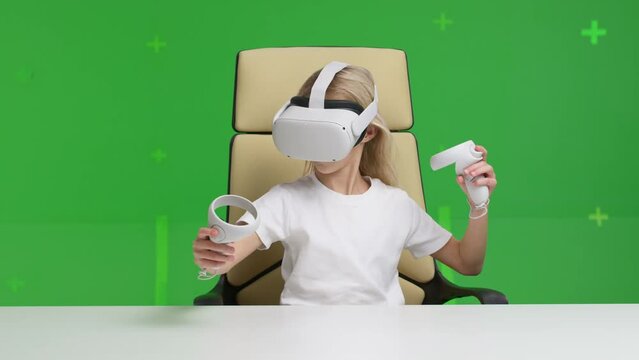 Beautiful young girl wearing virtual reality headset. Augmented Reality. Happy cute kid touch something using modern 3D glasses indoors. Woman playing using VR goggles over green screen