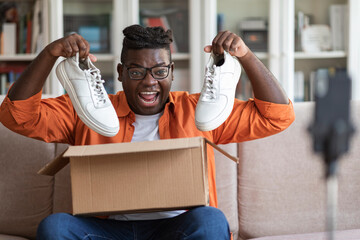 Emotional black guy fashion blogger showing brand new sneakers