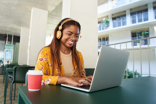Young black African woman university student learning online using laptop computer. Smiling girl watch webinar or virtual education remote class studying outdoor sitting outside campus
