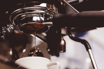 Process professional espresso pouring from coffee machine in cafe, warm toning
