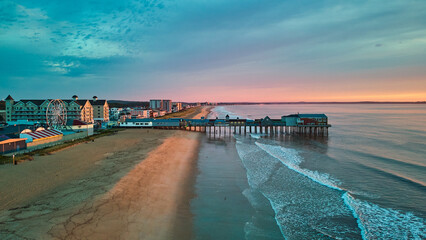 Obraz premium Aerial view over beach in Maine during sunrise with town and old wood pier of shops