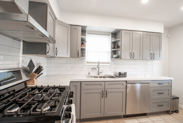 Beautiful Kitchen with a gas stove top and hood fan in a small kitchen with white back splash.