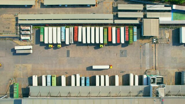 4K : Many of Semi-trailer trucks stand at the distribution center. cargo import export shipment. Industrial containers cargo shipment. consumption and transportation concept. aerial view footage.
