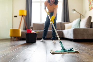Smiling Young Woman Washing Floor In Living Room With Mop