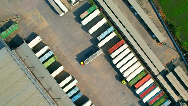 4K : Many of Semi-trailer trucks stand at the distribution center. cargo import export shipment. Industrial containers cargo shipment. consumption and transportation concept. aerial view footage.
