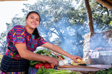 Retrato de mujer con vegetales fresco para preparar un platillo tradicional de Guatemala. Mujer indigena cocinando al aire libre.