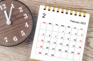 The February 2023 Monthly desk calendar for 2023 year with wooden clock.