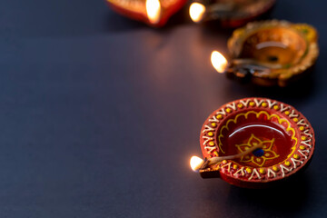 Happy Diwali, Diya lamps lit during Diwali celebration on black background.