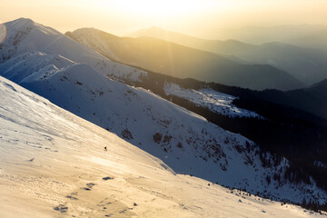 A freerider snowboarder descends a wide slope against the background of mountain ranges and the...