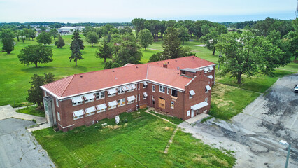 Old abandoned brick building aerial surrounded by trees