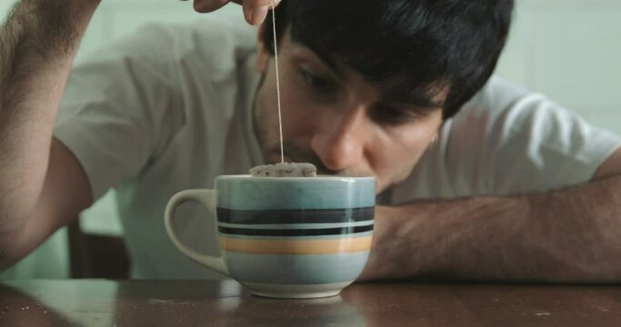 apathy, depression - alienated man stares at the tea bag spinning 