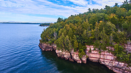 Aerial over cliffs on Vermont coast with lush green forest above