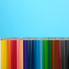 Colorful pencils on light blue background, flat lay. Space for text