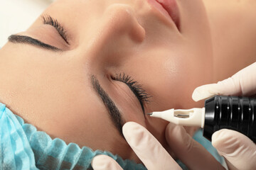 Young woman undergoing procedure of permanent eyeliner makeup, closeup - obrazy, fototapety, plakaty