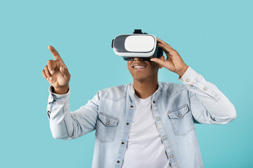 Smiling young african american male in casual and vr glasses has fun, enjoy technology alone, touch air