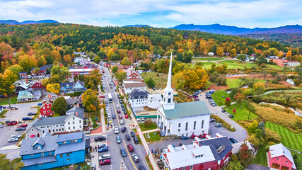 Beautiful aerial view over small Vermont town of Stowe in peak fall foliage with focus on church