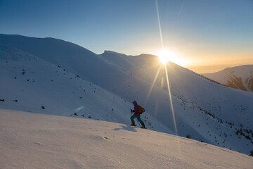 A skier climbs to the top in the rays of the morning sun
