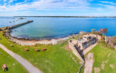 Old military fort on coast of Maine with pier and small island lighthouse in distance