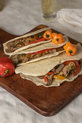 Tacos, typical Mexican food, with beef, vegetables and spices on a wooden board.