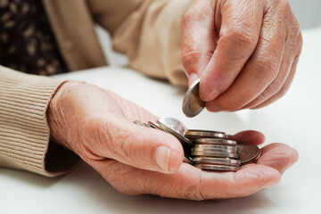 Retired elderly woman counting coins money and worry about monthly expenses and treatment fee...