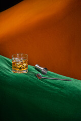 alcoholic drink with ice on a green and orange abstract space with bartender kit