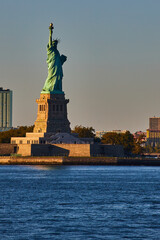 Light filling in half of Statue of Liberty in New York City from waters with golden hues