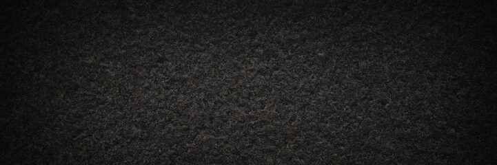 Dark granite texture. Natural granite with a grainy pattern. Solid rough surface of rock with spots, noise and grain. Dark stone background for design. Shaded texture with vignette.