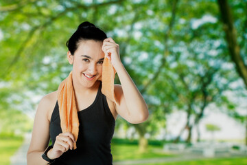 Smiling woman wiping sweat after workout at park