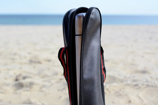 Metallic thermos in black stylish case on sandy beach © New Africa