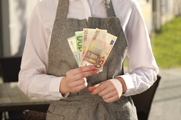 Waitress holding payment for order and tips at outdoor cafe, closeup