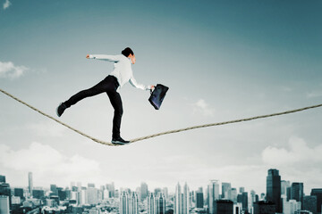 Businessman running on the rope above the city