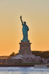 Fototapeta na wymiar New York City golden hour light around iconic Statue of Liberty in dusk