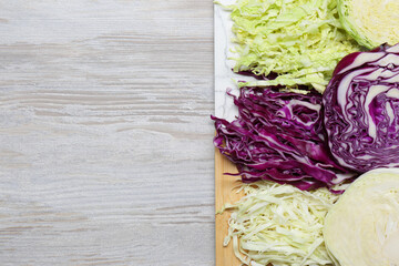 Different types of cut cabbage on white wooden table, top view. Space for text