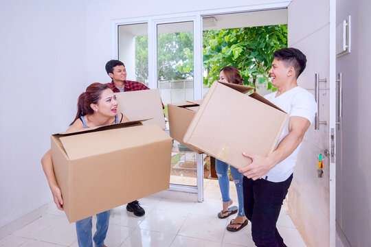 Group of people carrying cardboard into new house