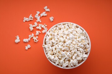 Bucket of tasty popcorn on orange background, flat lay