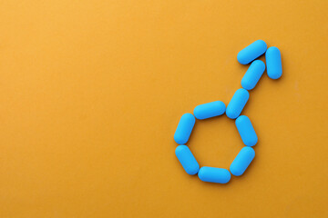 Pills and space for text on orange background, top view. Potency problem