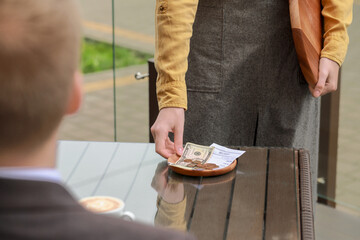 Waitress taking tips from wooden table in outdoor cafe, closeup