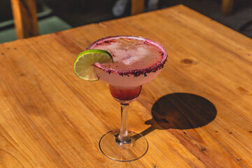 Colorida margarita sabor a limón con tequila decorada con granada y una rebanada de limón.