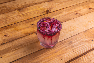 Mezcal con hielos, limón y granada en un vaso escarchado con sal.