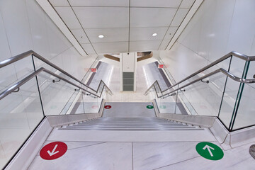 Super clean white subway stairs leading down to trains with red and green arrow graphics