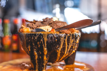 Molcajete de piedra volcánica 3 carnes, carne asada, pulpo, camarón, con queso fundido, chile ancho, pimiento y salsas, con una cerveza y tortilla, Platillo típico mexicano