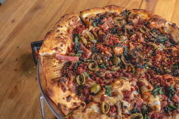 Pizza a la leña con ingredientes variados como carne, cebolla, pimiento, chorizo, jamón. 