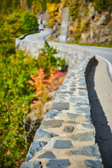 Beautiful stone wall winding along road that zig zags through mountain cliffs into distance