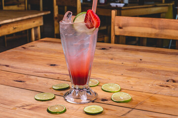 Colorida soda italiana de fresa con limón, tequila y hielo sobre una mesa de madera en un...