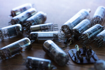 50's 60's vacuum tube or valves on old wooden table with incoming light. Shallow depth of field. - obrazy, fototapety, plakaty
